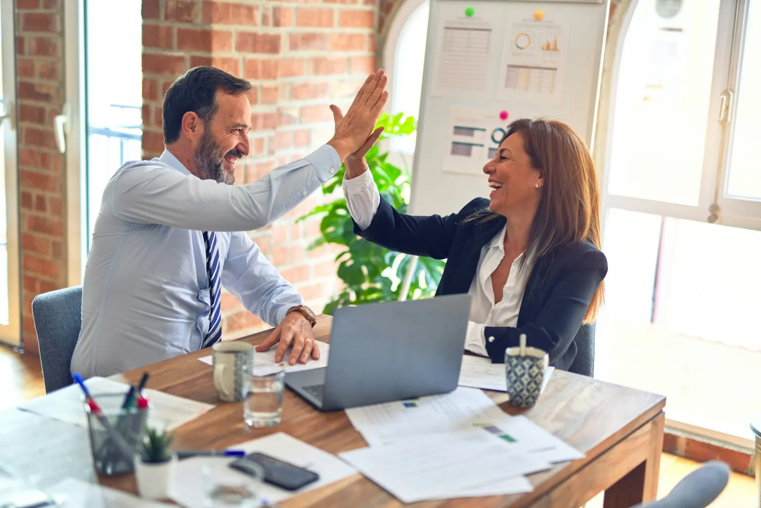 Two business people celebrating across a desk